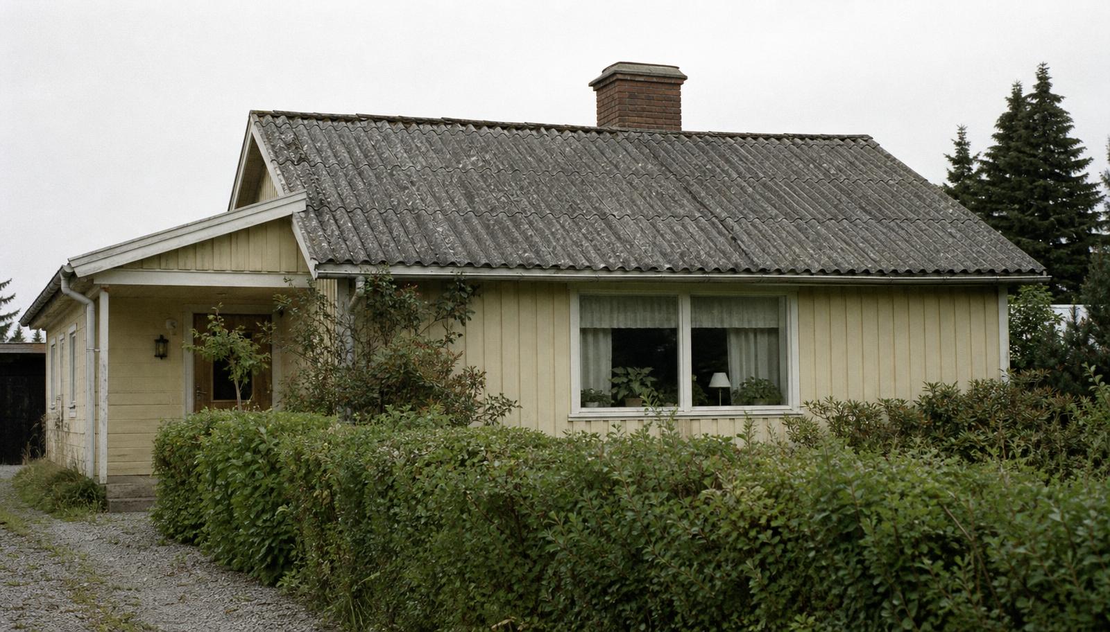 Äldre svensk villa med grått eternittak av asbestcement med mossa och slitage